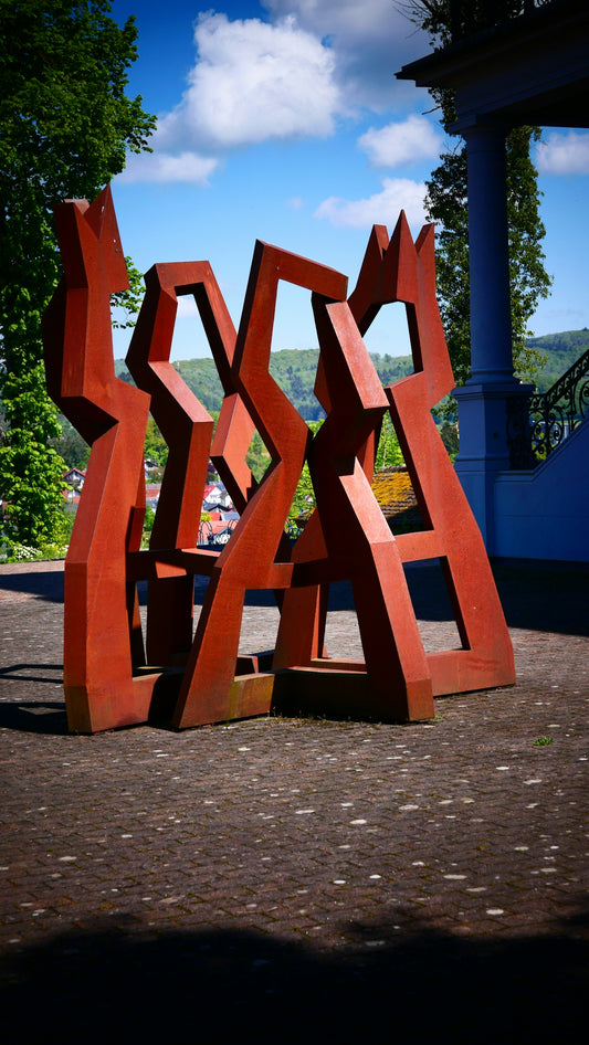 a large red sculpture sitting on top of a sidewalk