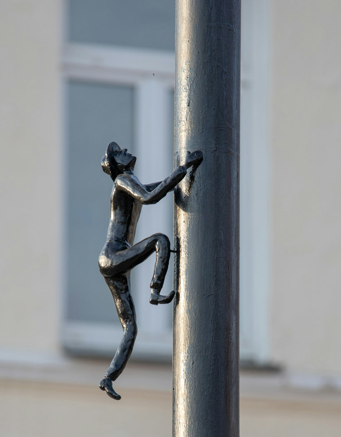 a statue of a person climbing up a pole