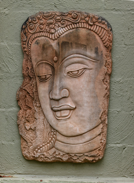 a stone carving of a buddha head on a wall