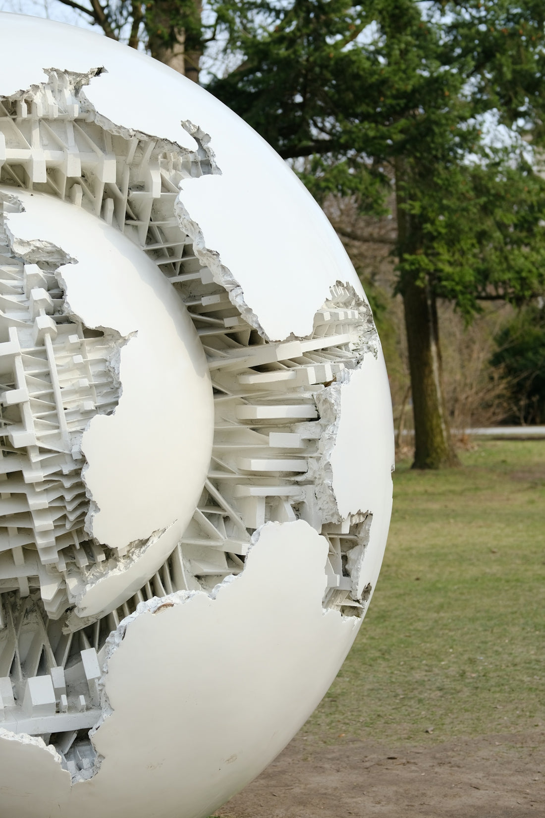 a large white sculpture in a park with trees in the background