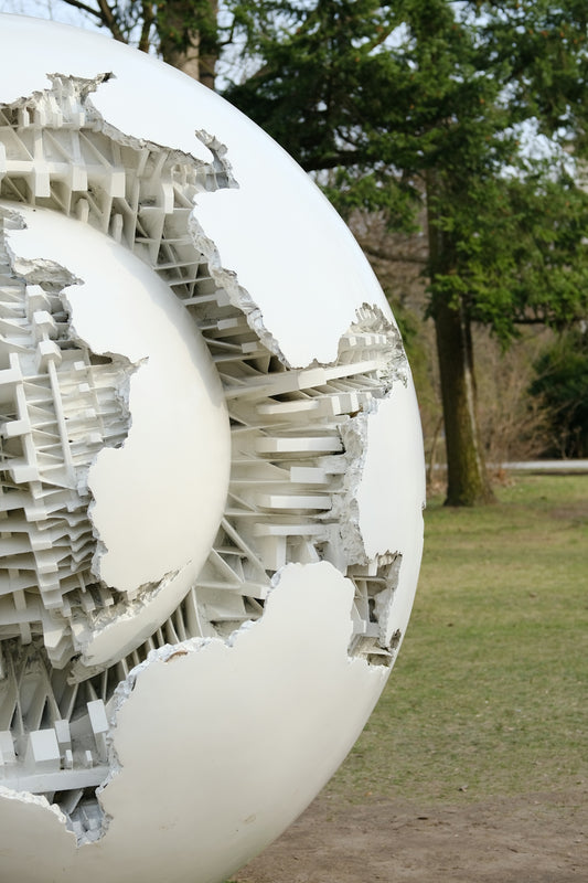 a large white sculpture in a park with trees in the background