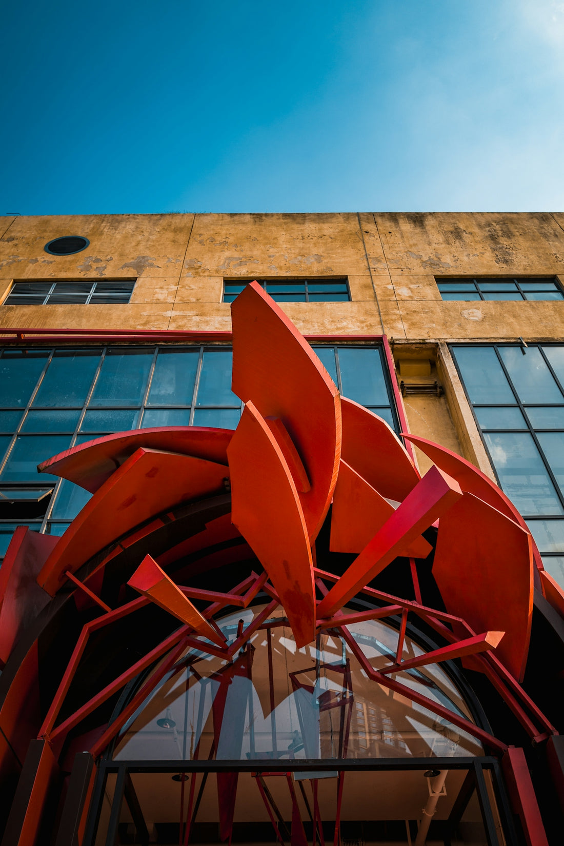 a large orange sculpture in front of a tall building