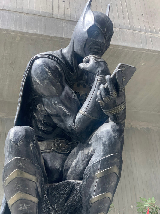 a statue of a batman reading a book