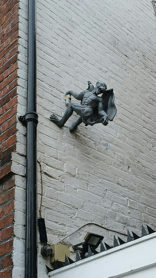 A statue of a demon on a brick wall