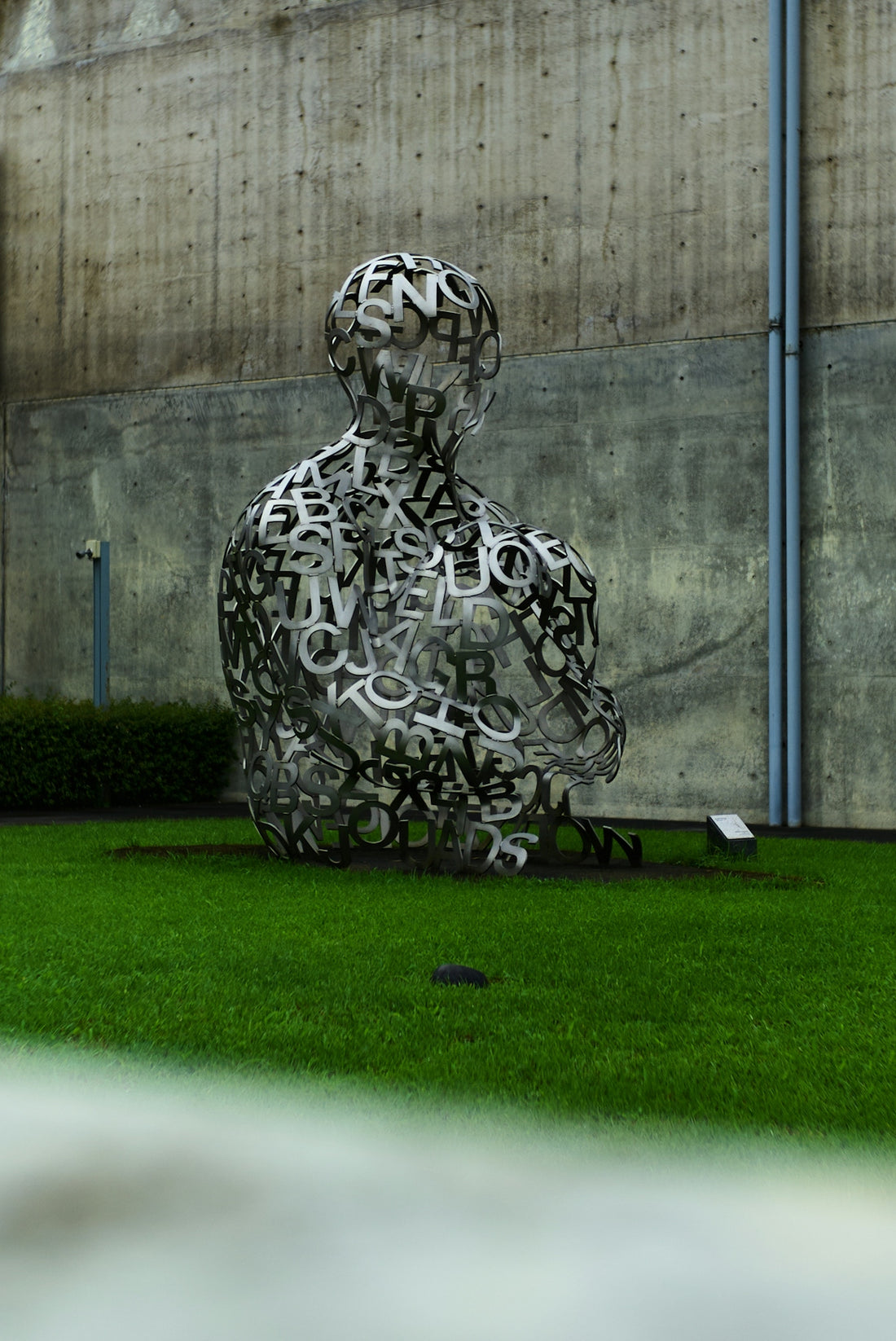 A sculpture of a person sitting in the grass