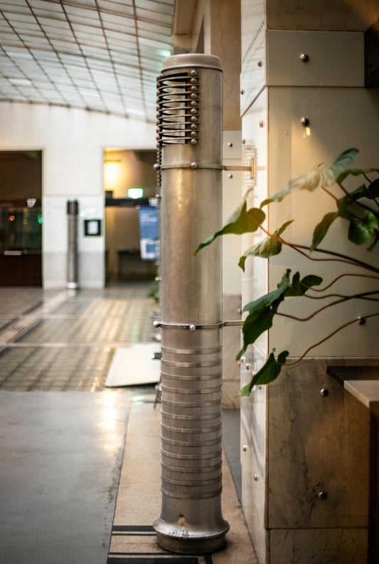 An industrial pillar stands near greenery in a building.