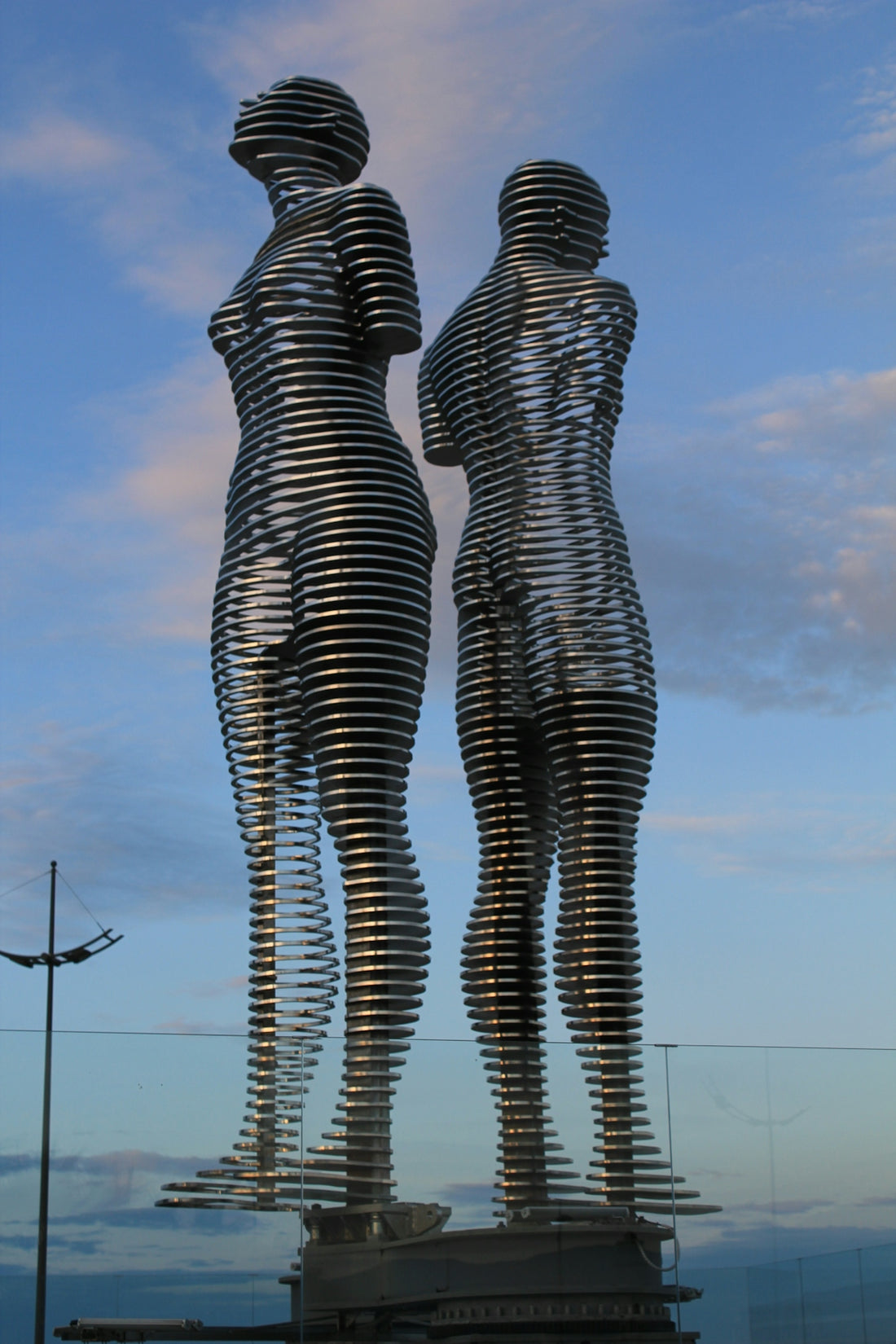 Two metal sculptures stand tall against a sky.