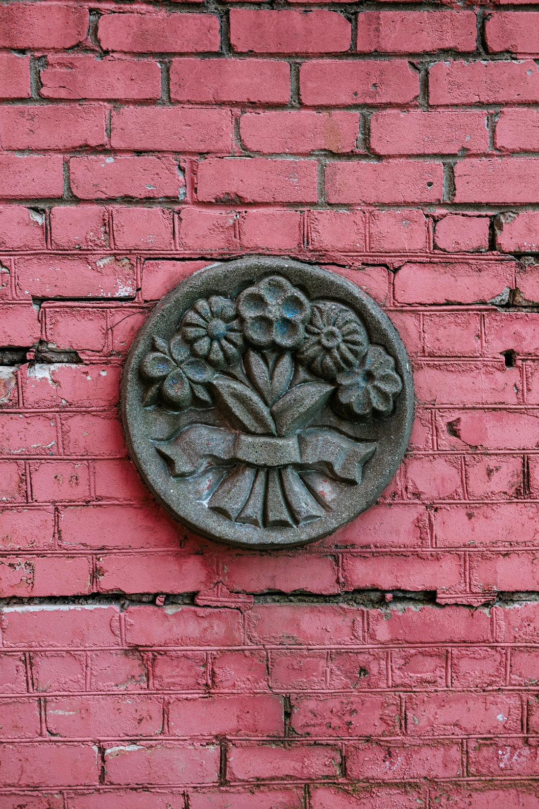 Circular floral relief mounted on pink brick wall
