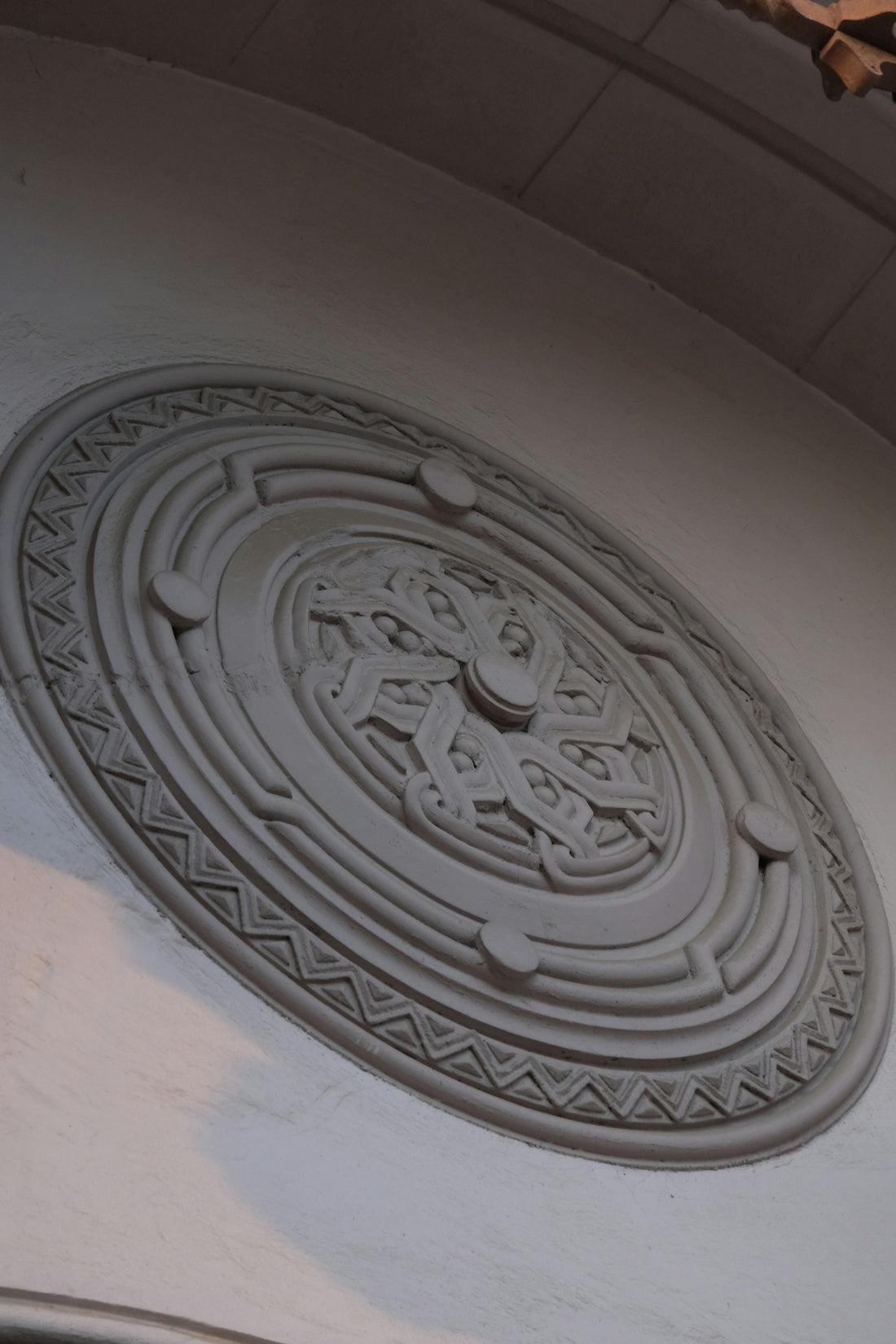 Ornate circular relief carving on a white wall.