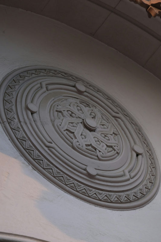 Ornate circular relief carving on a white wall.