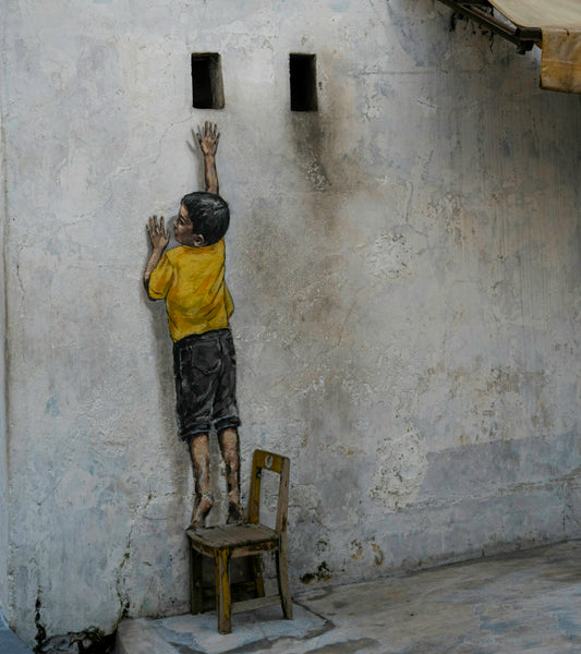 Boy on chair reaching for holes in wall