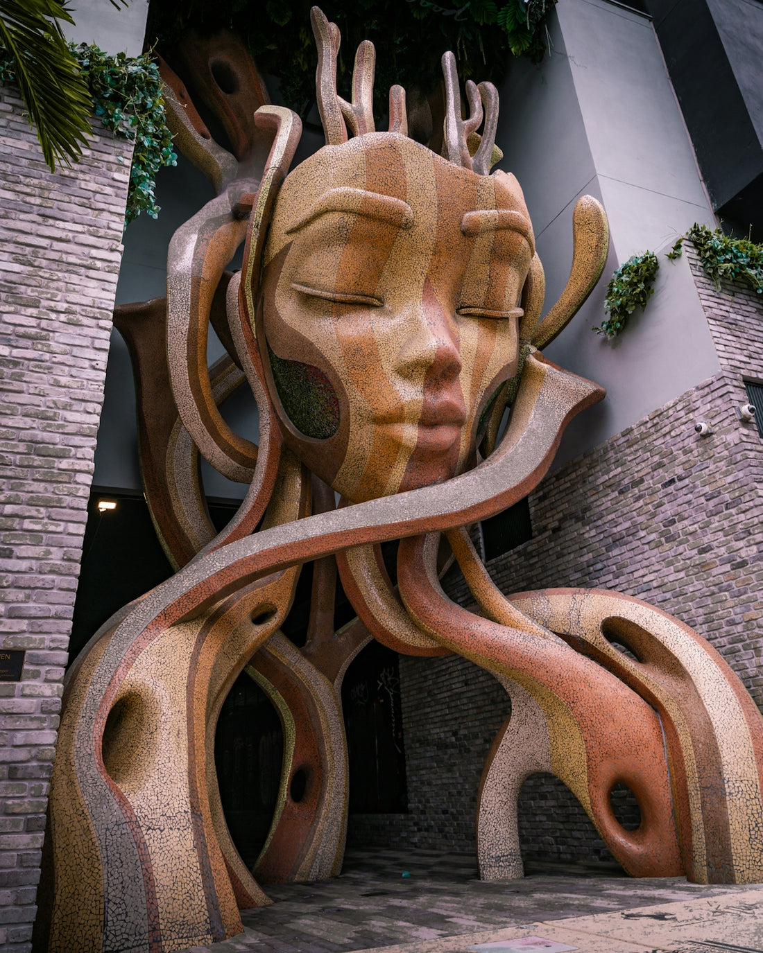 Abstract mosaic sculpture of a serene face with flowing elements.
