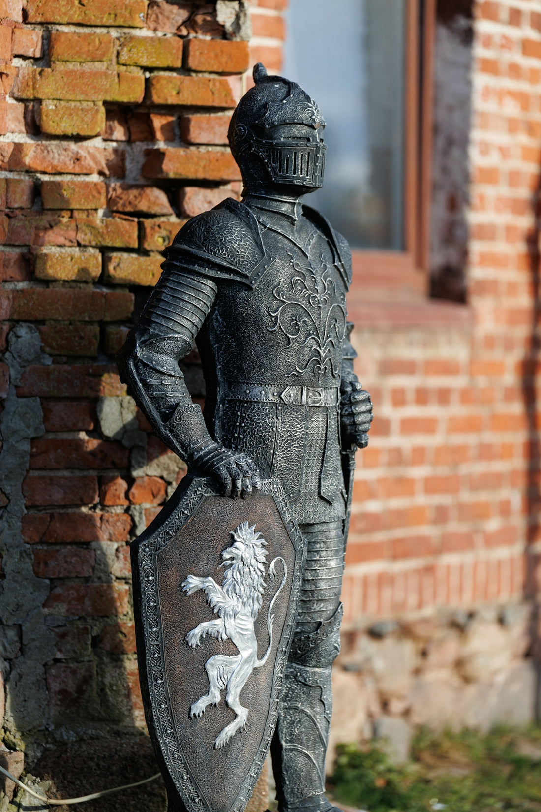 Knight statue holding a shield with a lion emblem.