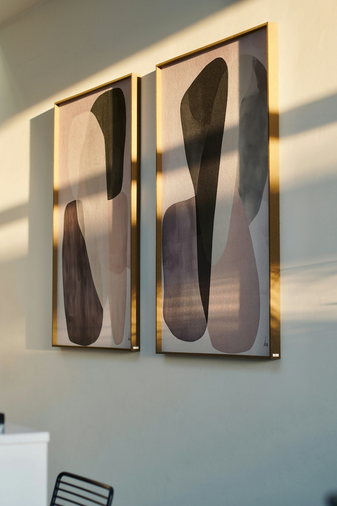 Two abstract paintings with gold frames on wall.