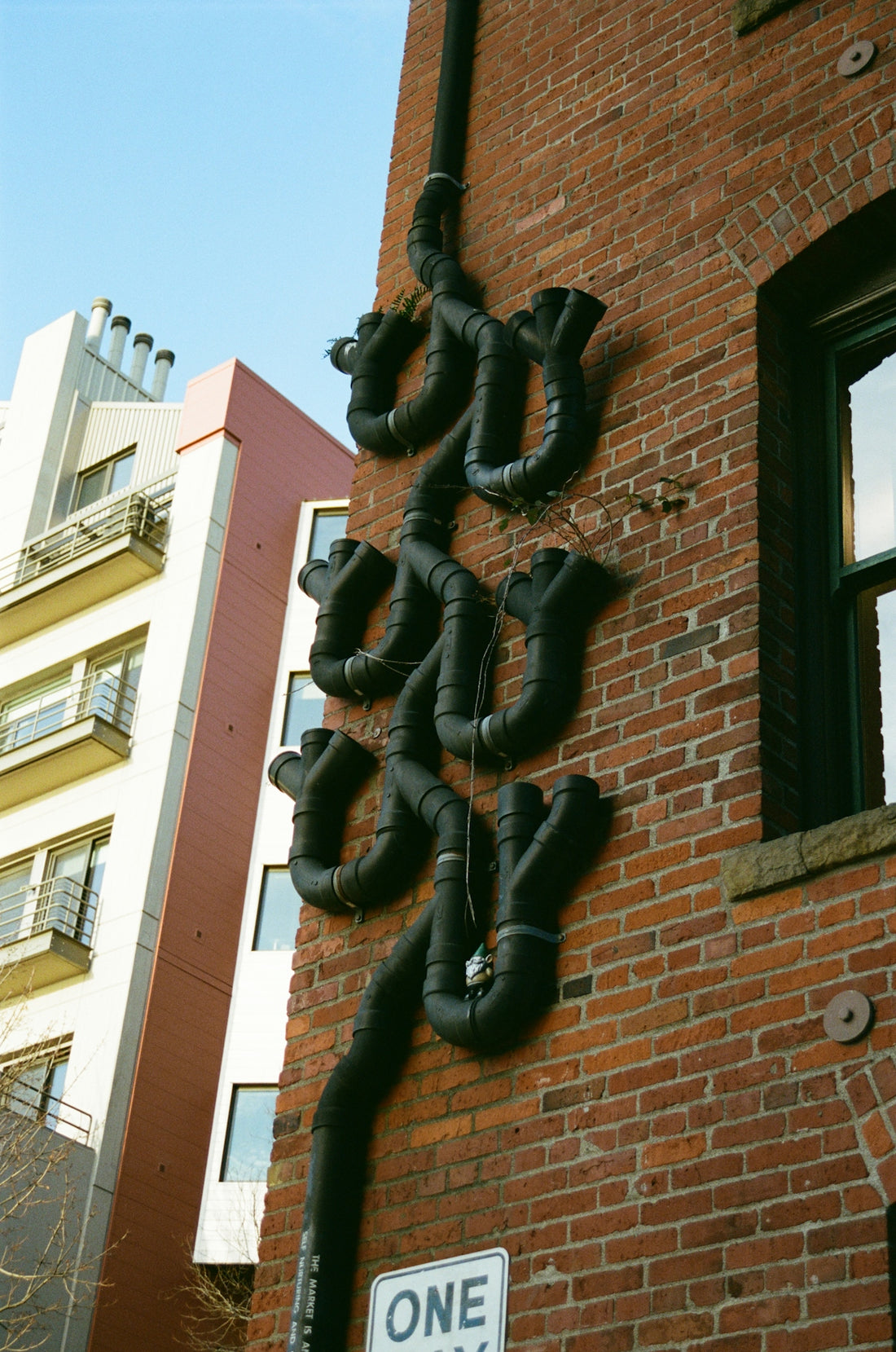 Black pipes form an artistic design on a brick wall.