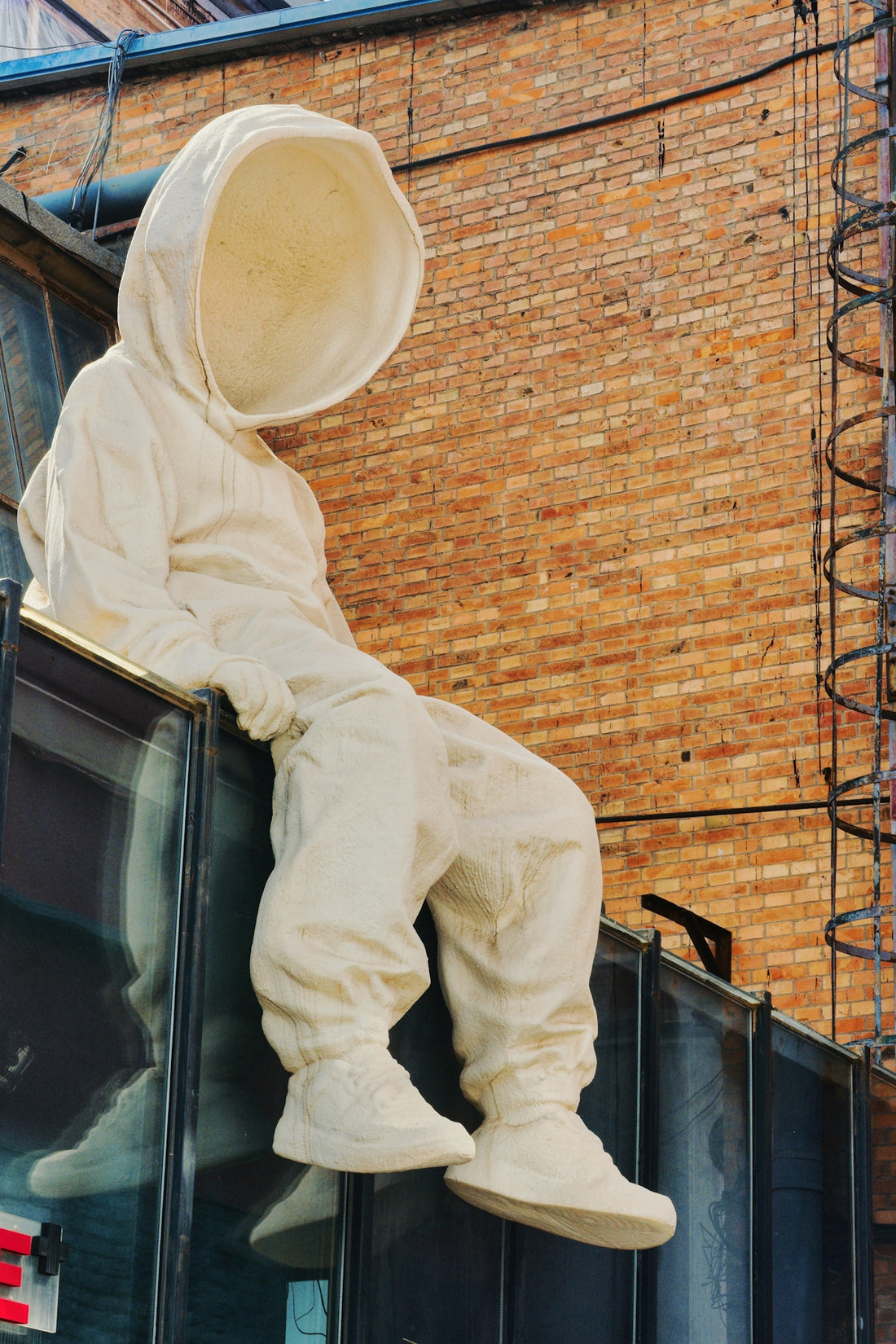 A white hooded figure sits on a ledge.