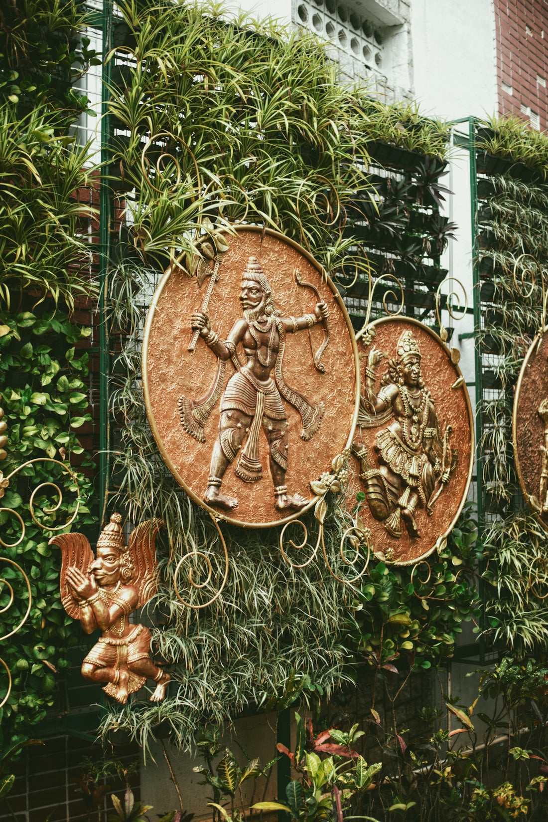 Embossed medallions depicting hindu deities on a green wall