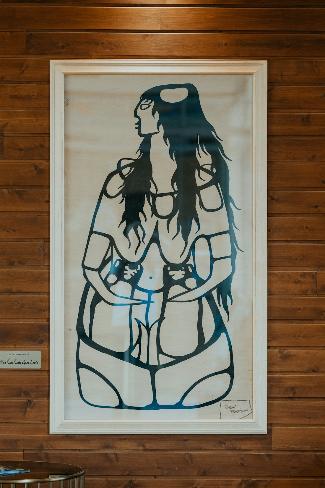 Framed artwork of a stylized figure on a wooden wall