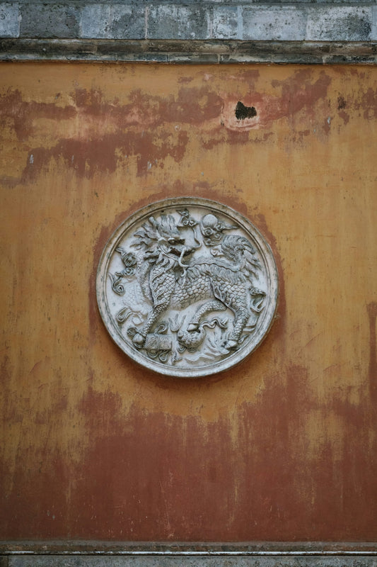 Circular stone carving of a dragon on a weathered wall.
