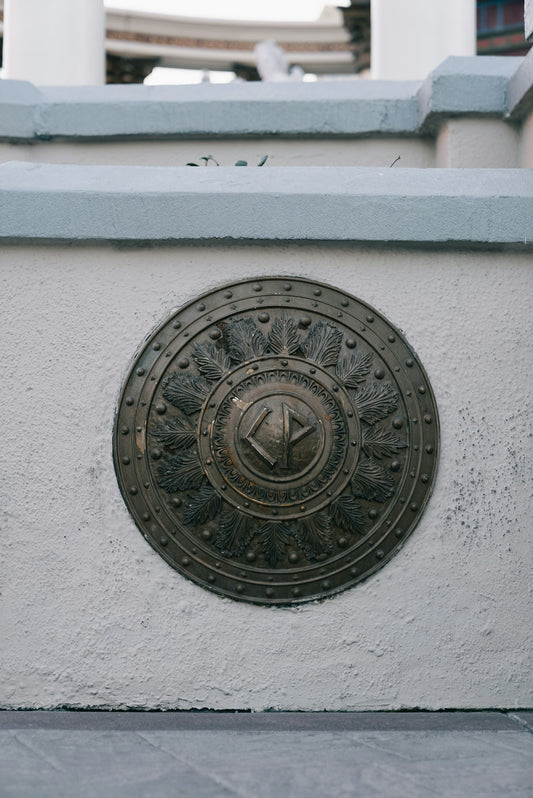 Round bronze emblem with intricate design on wall