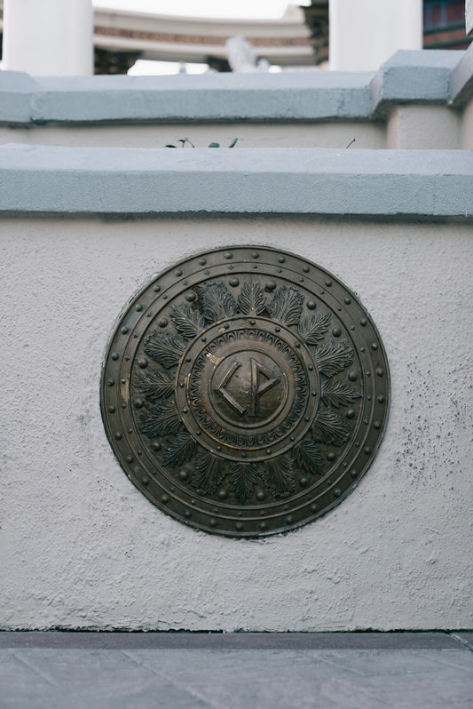 Round bronze emblem with intricate design on wall