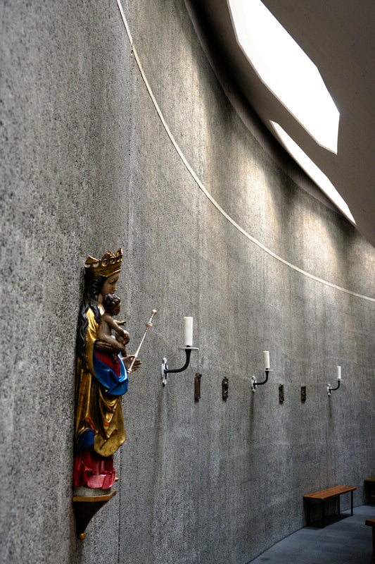 Statue of mary holding baby jesus on textured wall