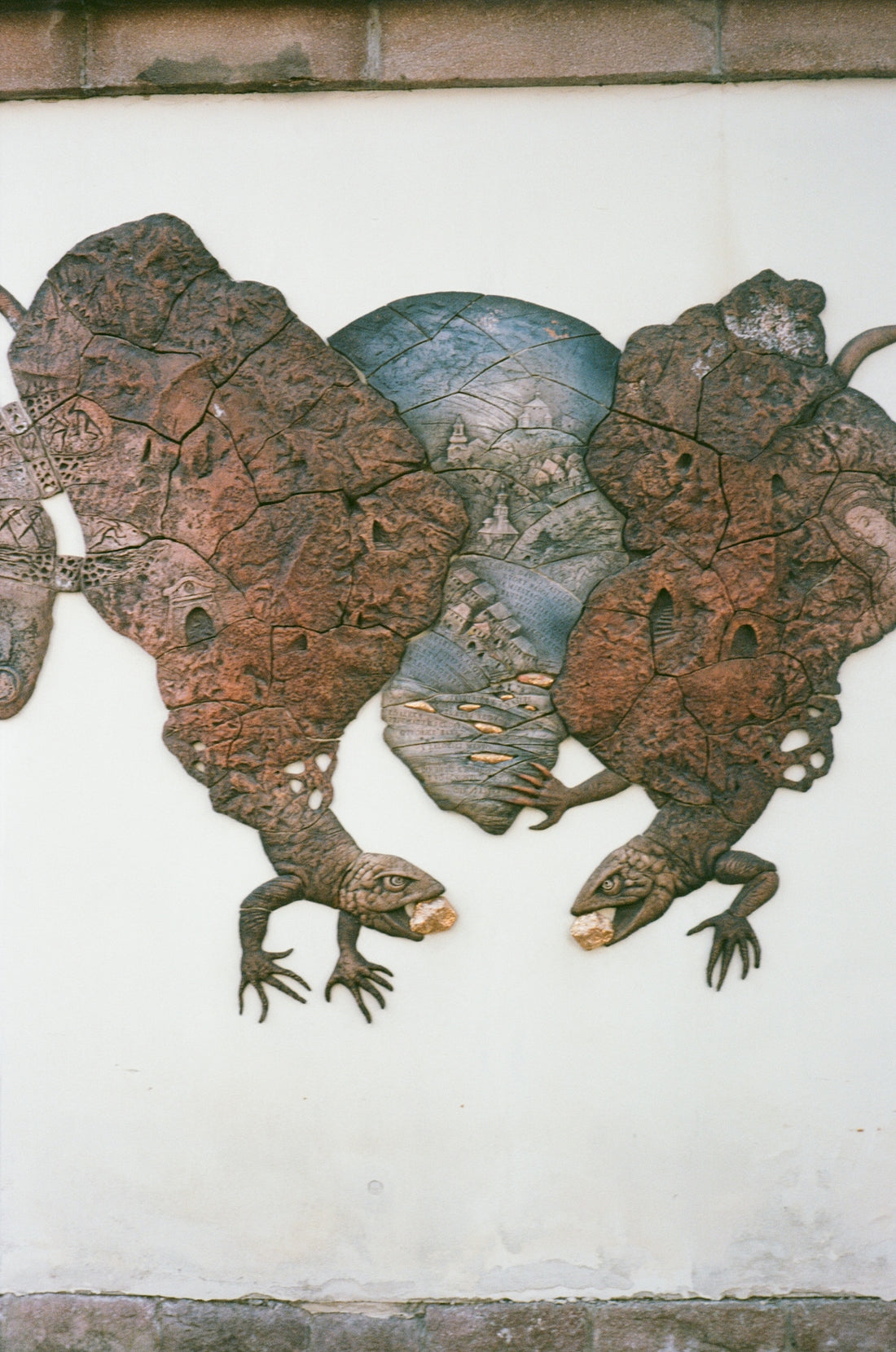 Wall relief depicting two lizards and a central landscape scene.