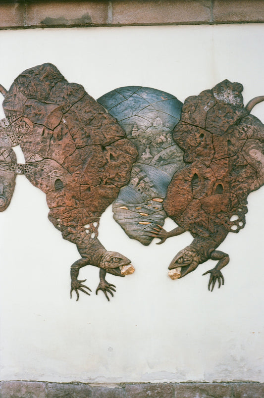 Wall relief depicting two lizards and a central landscape scene.