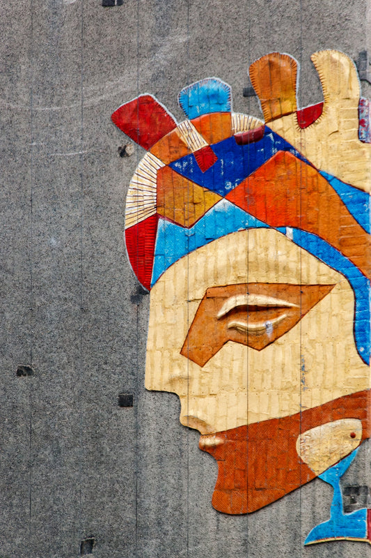 Colorful abstract face mosaic on a grey textured wall.