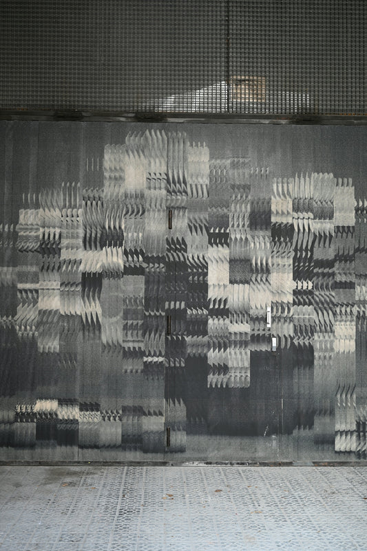 Abstract pixelated grayscale pattern on a textured wall.