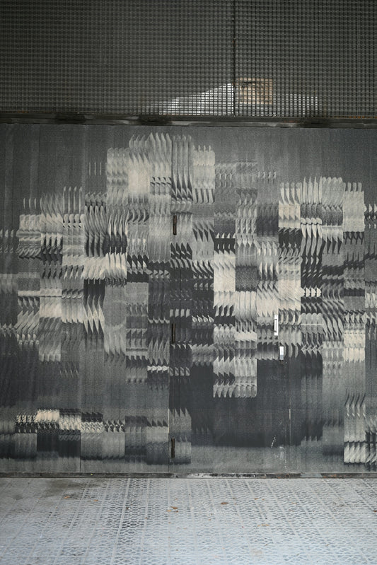 Abstract pixelated grayscale pattern on a textured wall.
