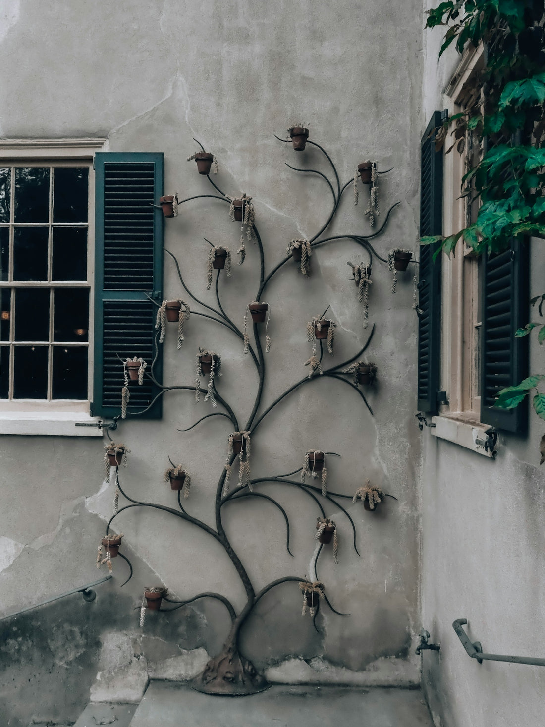 Decorative metal tree sculpture on a weathered stucco wall