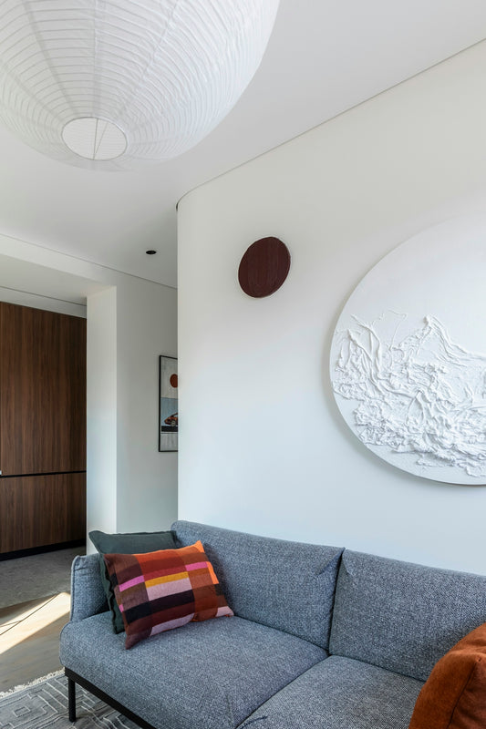 Contemporary living room interior with sofa, art, and paper lantern.