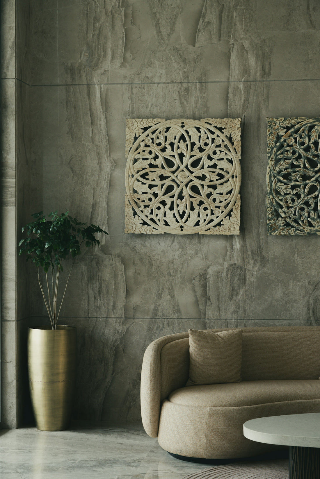 Modern lobby with beige sofa, plant, and carved wall art.